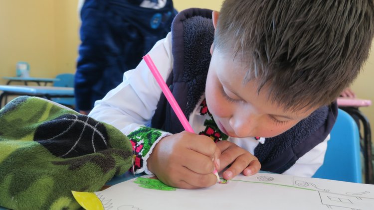 A student with a pink pencil writes a message on a piece of paper