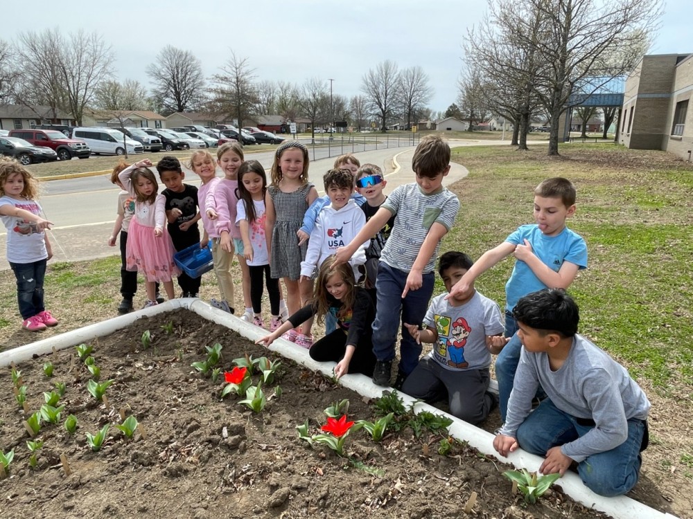 Kids pose with two blooming red tulips