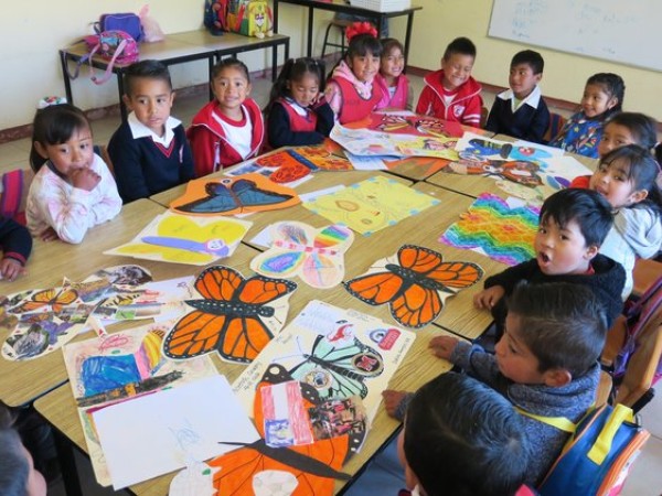 children in Mexico sitting at a round table looking at ambassador butterflies