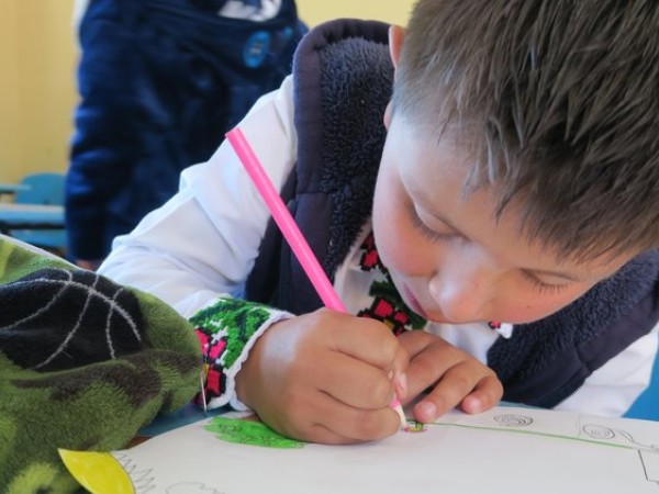 A student with a pink pencil writes a message on a piece of paper